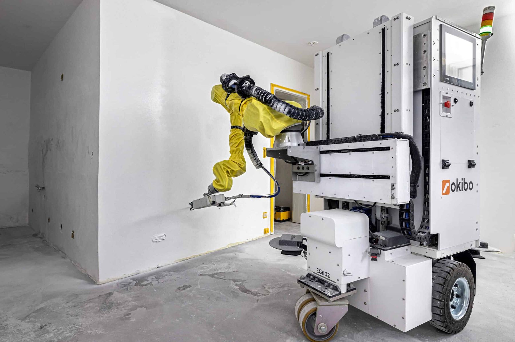 Okibo robot positioned at a wall in an unfinished room
